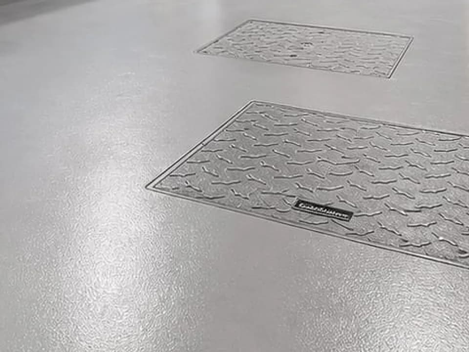 Close-up of the epoxy floor at Villa G28: smooth, glossy finish running cleanly around two floor access covers