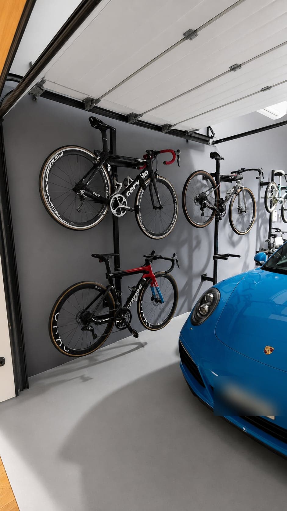 Four road bikes stacked two-high on wall racks beside the parked car in the G28 garage