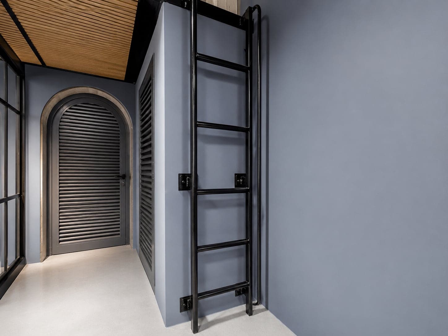 Welded steel access ladder to the mezzanine storage platform, beside the arched louvred door
